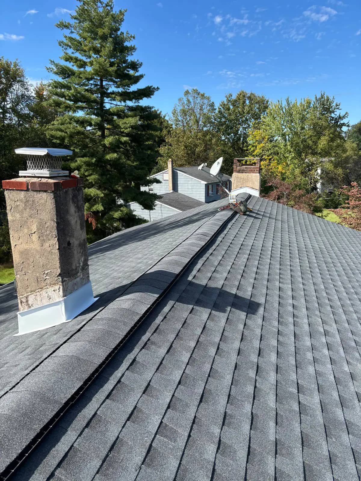 Completed Charcoal shingle slopes and ridge between chimneys on the Chalfont roof